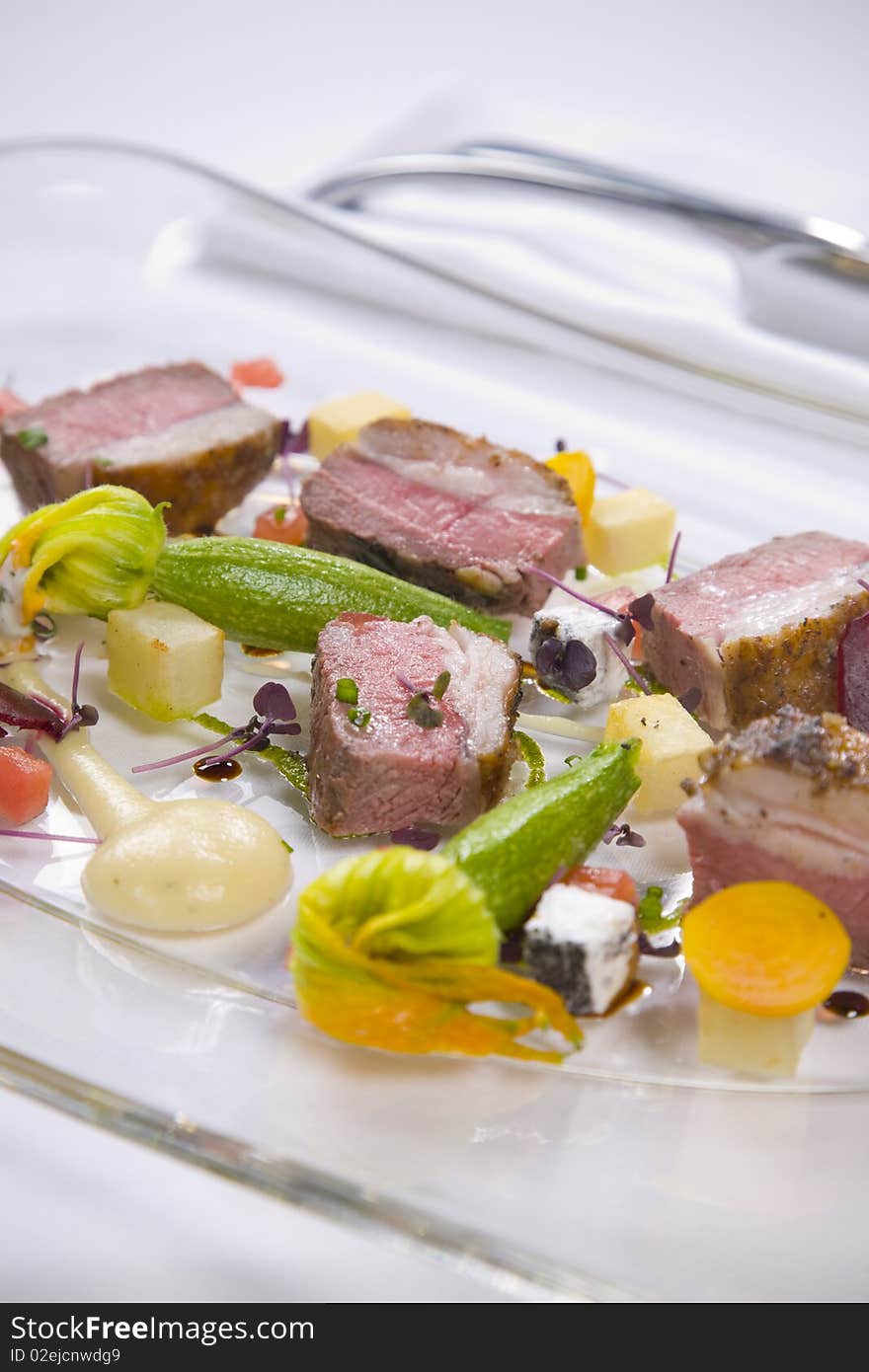 Lamb served with vegetables and sauce served on glass designer plate