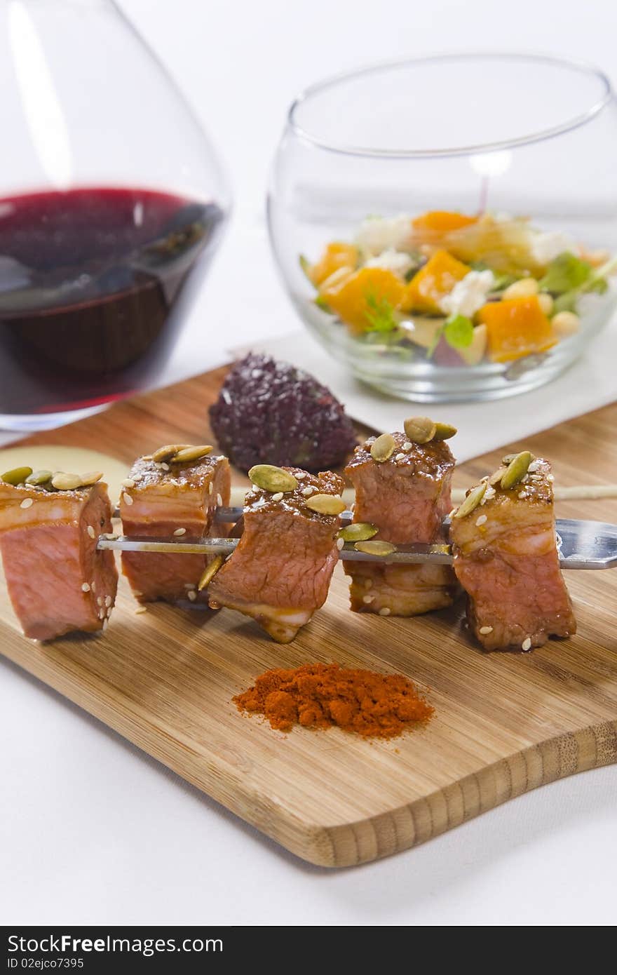 Beef served on skewers with condiments and red wine