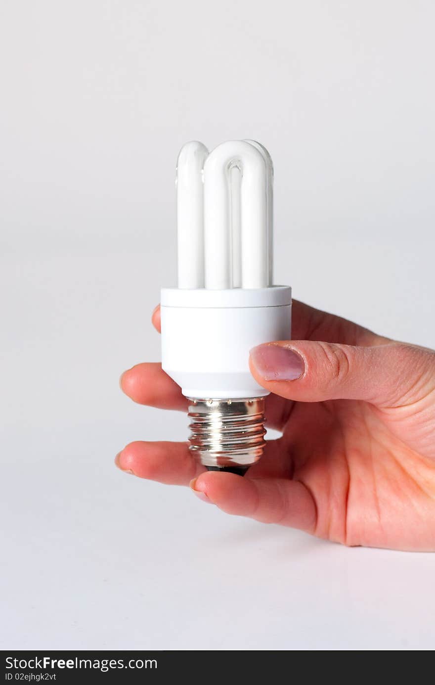 A hand holding a low energy lamp isolated against i white background. A hand holding a low energy lamp isolated against i white background