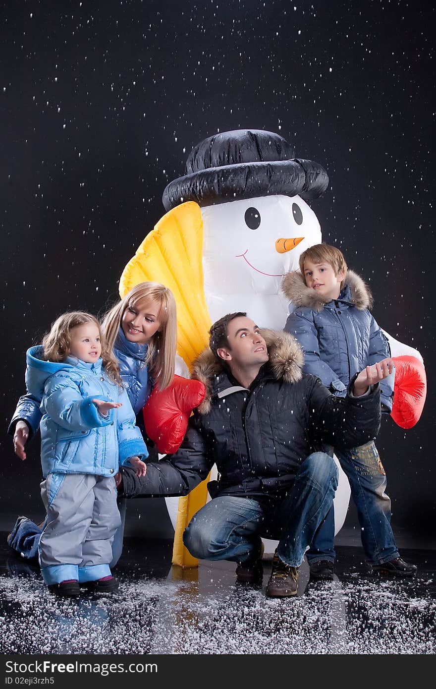 Young woman, man and children olaying near the big snow doll. Young woman, man and children olaying near the big snow doll