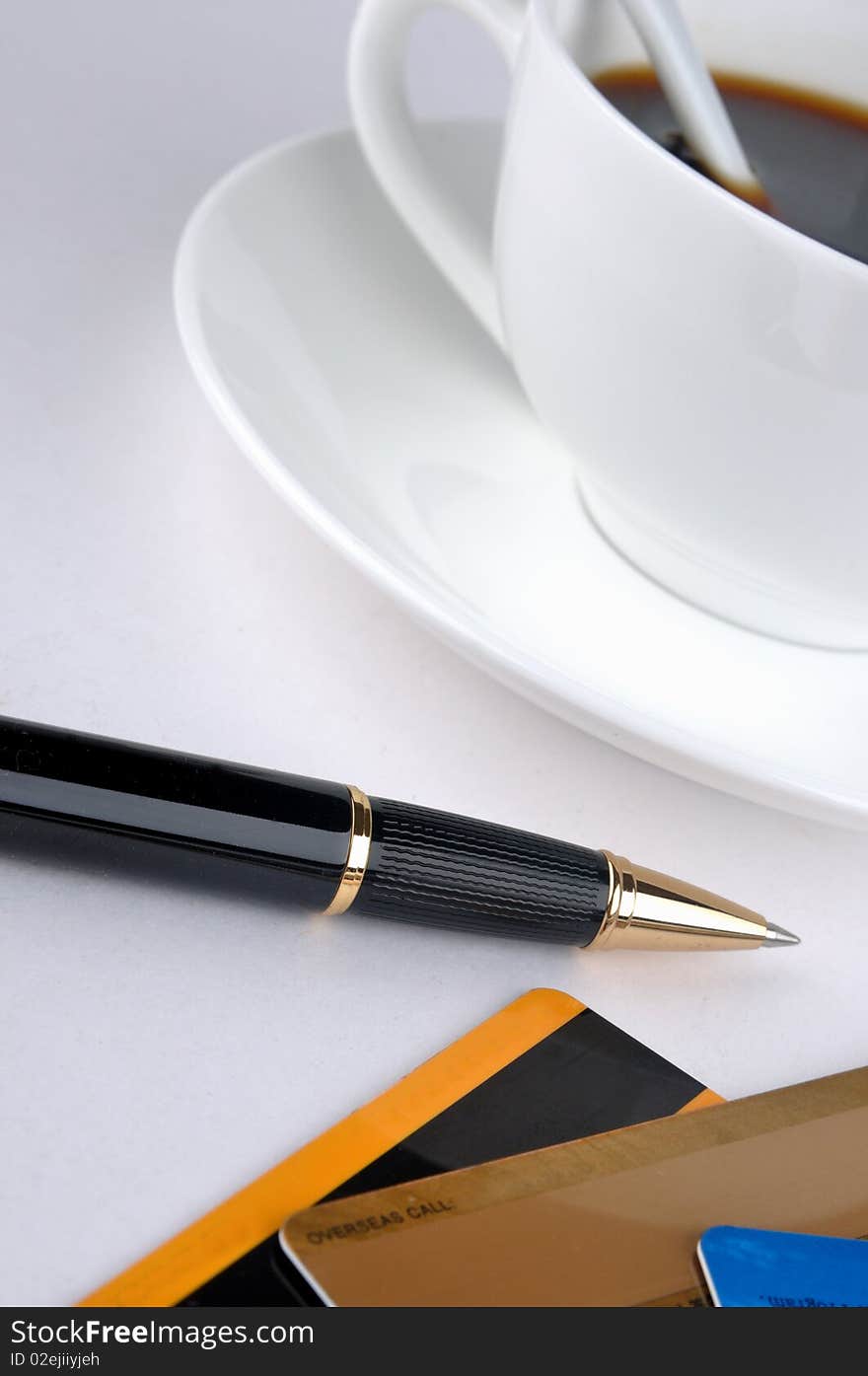 A cup of coffee and a ball pen with credit cards, means drinking, working, signature and relax. A cup of coffee and a ball pen with credit cards, means drinking, working, signature and relax.