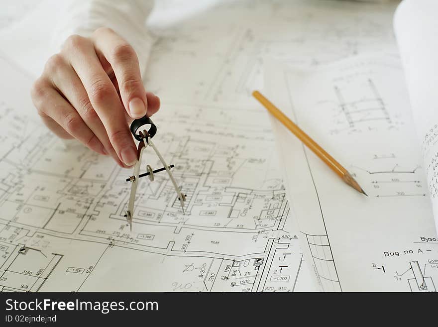 An image of metal calipers in a hand and a pencil, focus on a hand. An image of metal calipers in a hand and a pencil, focus on a hand