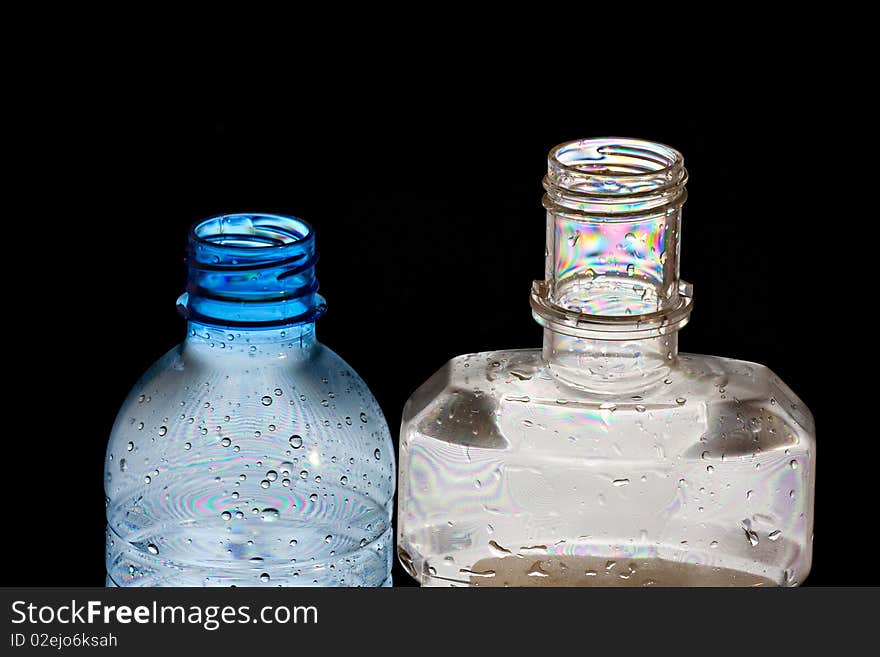 Two PET bottles in polarised light with colorful abstract patterns isolated on black. Two PET bottles in polarised light with colorful abstract patterns isolated on black