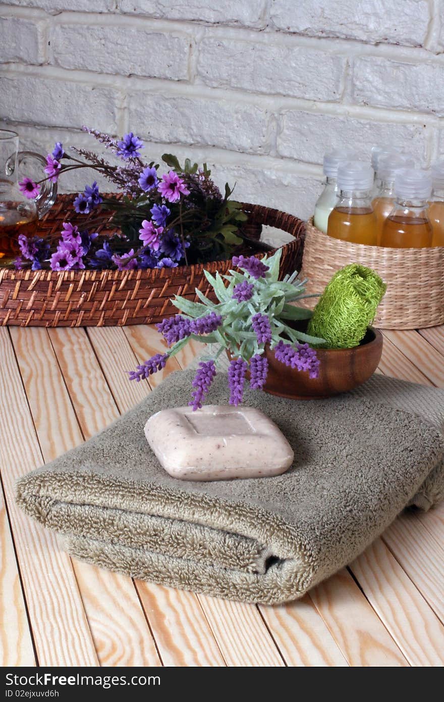 Towels,soap,fresh flowers in the wicker tray with massage oil in the wicker basket on the wooden floor. Towels,soap,fresh flowers in the wicker tray with massage oil in the wicker basket on the wooden floor.