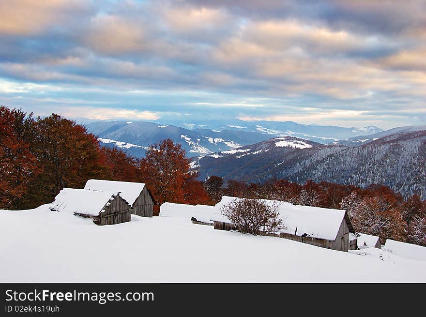 Sunrise in a mountain valley with huts and the first snow in October. Sunrise in a mountain valley with huts and the first snow in October