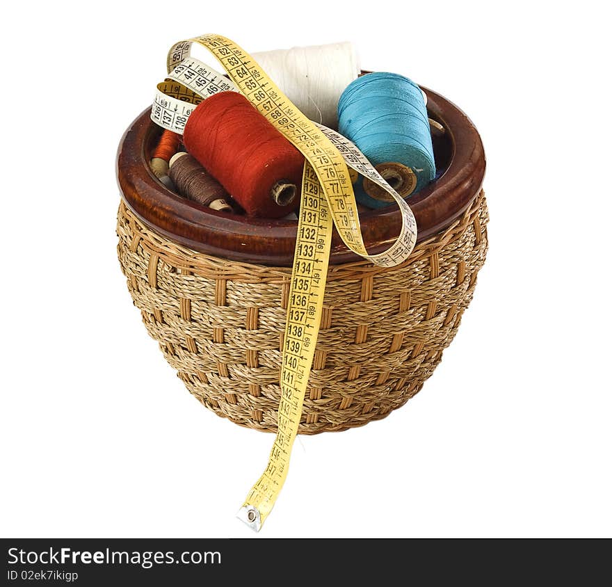 Basket with colour threads and a roulette on a white background. Basket with colour threads and a roulette on a white background