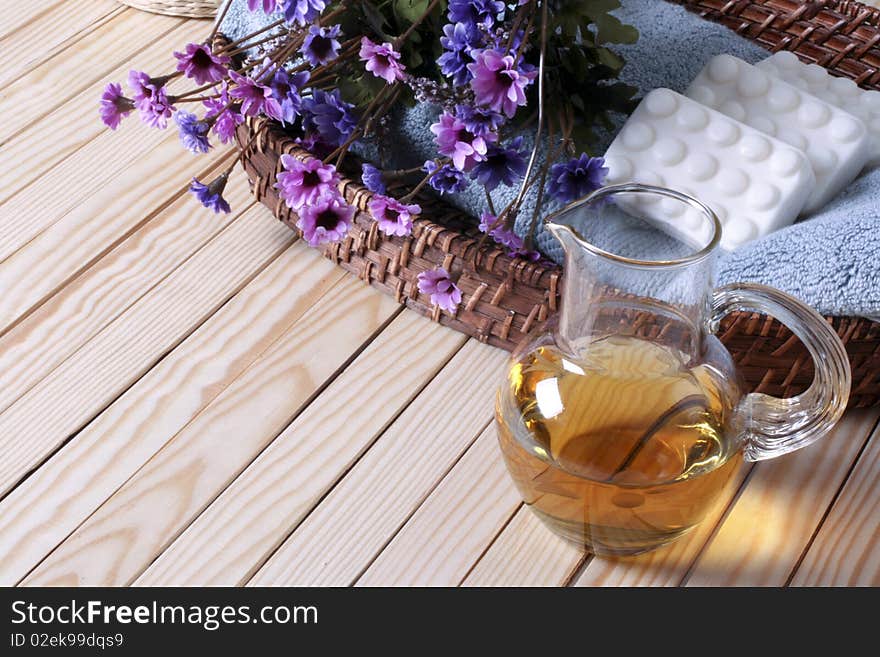 Wicker tray, towel, soaps, flowers and glass bottle on the wooden floor. Wicker tray, towel, soaps, flowers and glass bottle on the wooden floor.