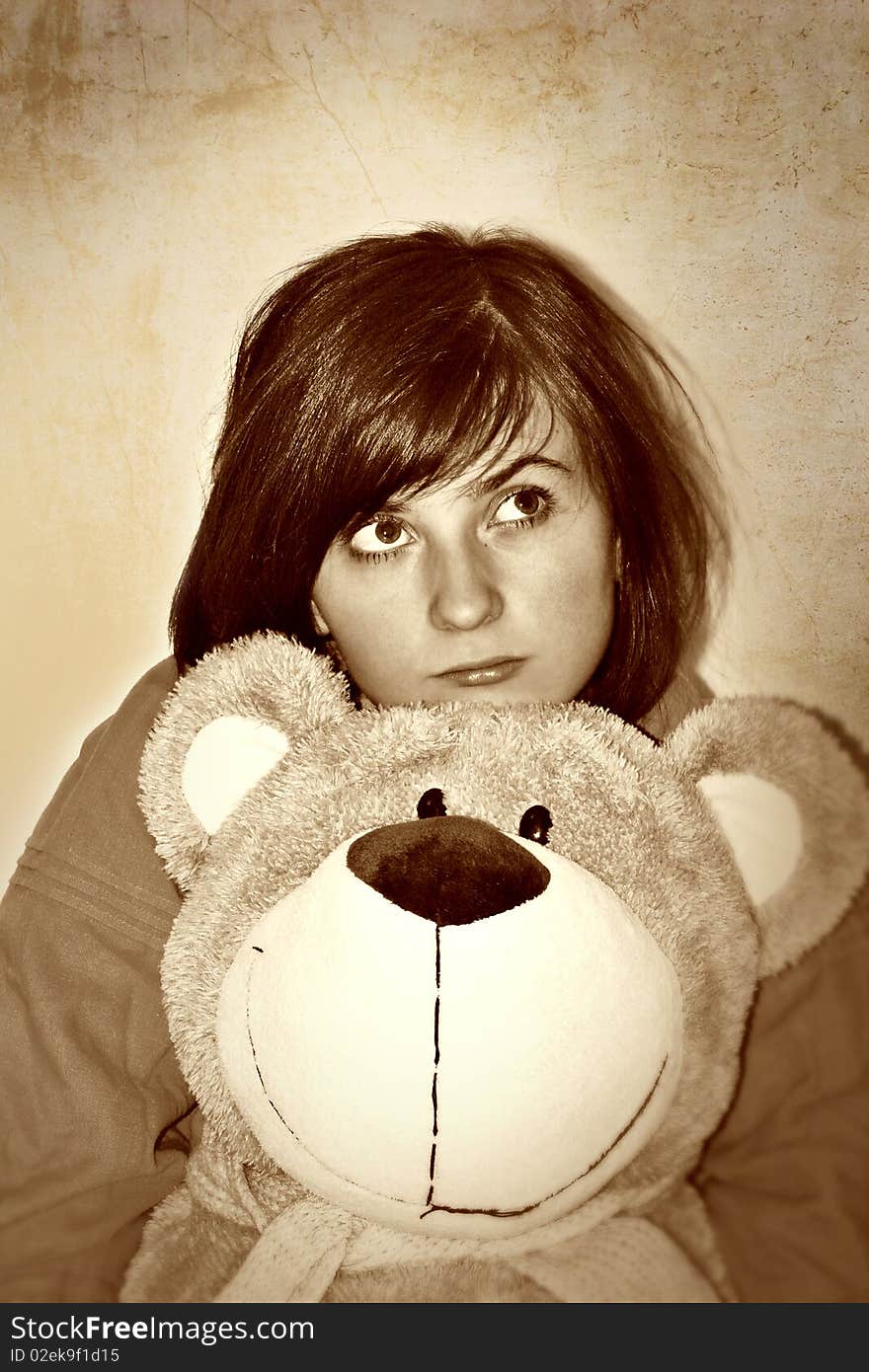 Sad girl with plush bear in hands