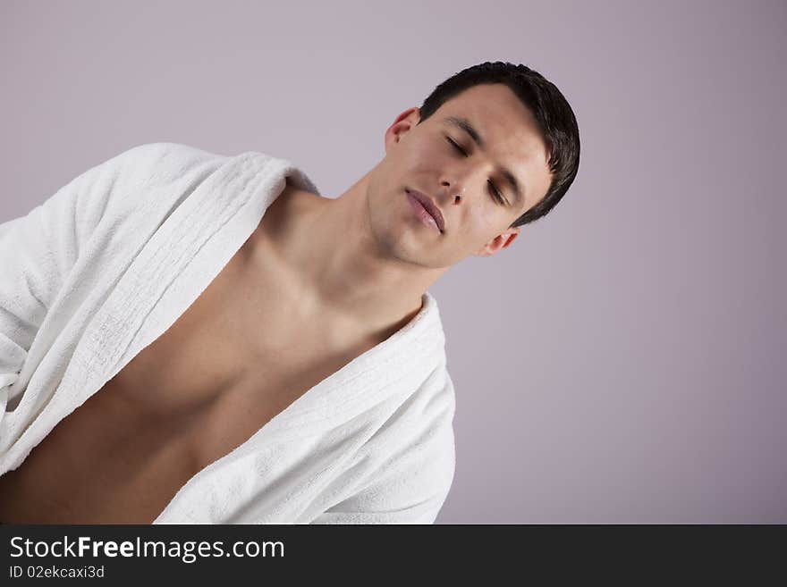 Handsome young man relaxing in the spa, wearing white towel robe. Handsome young man relaxing in the spa, wearing white towel robe.