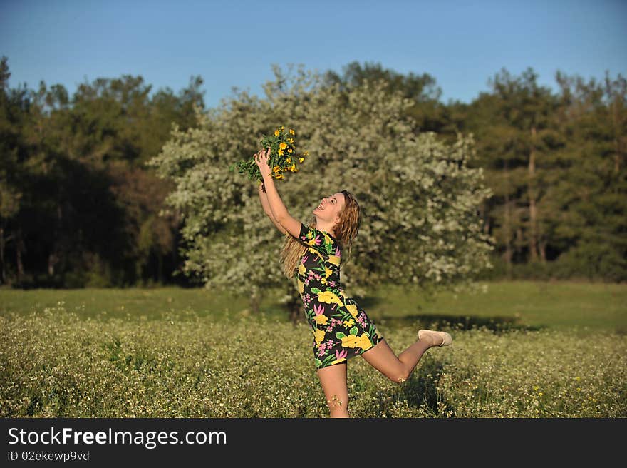 Beautiful young woman jumping in blooming meadow