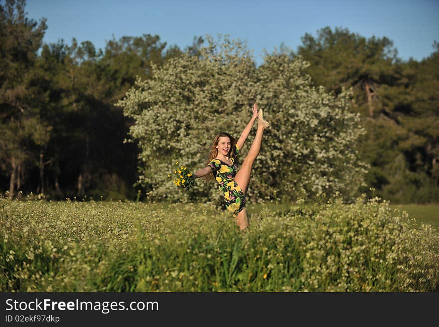 Beautiful young woman jumping in blooming meadow