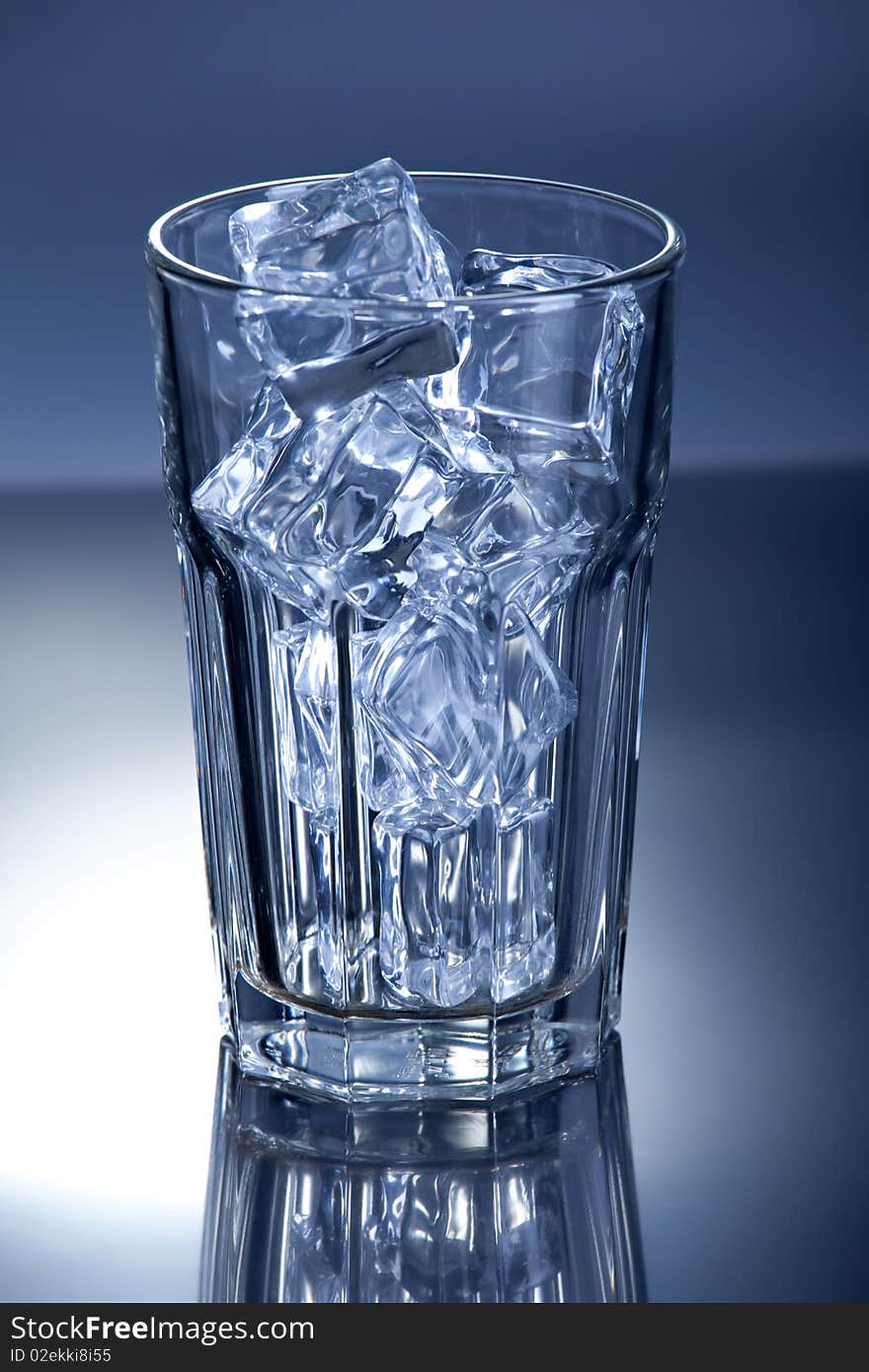 Glass of ice cubes on blue background