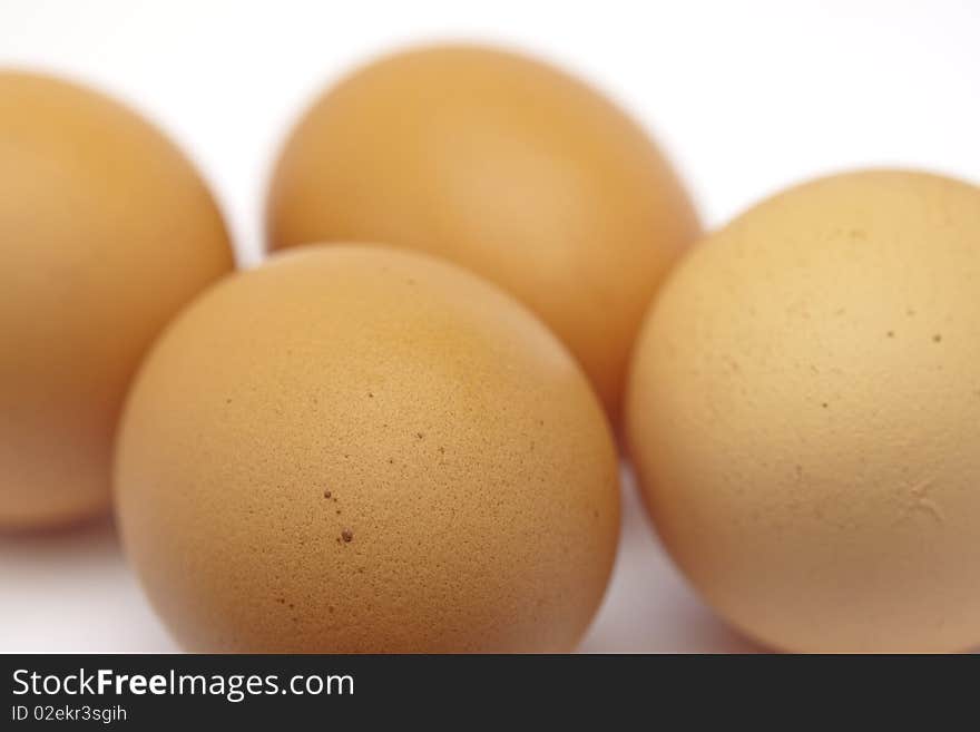 Four raw eggs on seamless white, uncracked