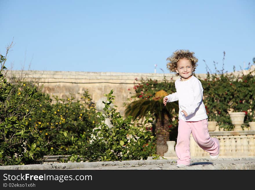 A young caucasian child with blond hair and blue eyes running happily. A young caucasian child with blond hair and blue eyes running happily