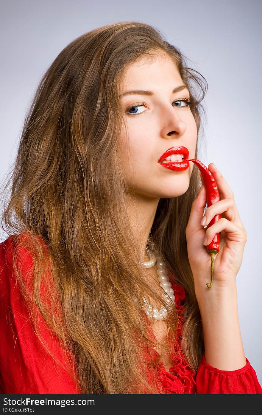 Portrait of a young beautiful girl holding her mouth red chili peppers. Portrait of a young beautiful girl holding her mouth red chili peppers