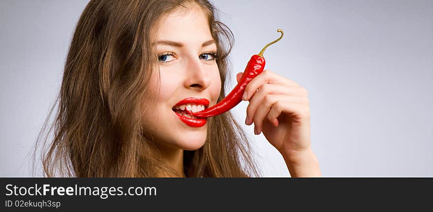 Portrait of a young beautiful girl holding her mouth red chili peppers. Portrait of a young beautiful girl holding her mouth red chili peppers