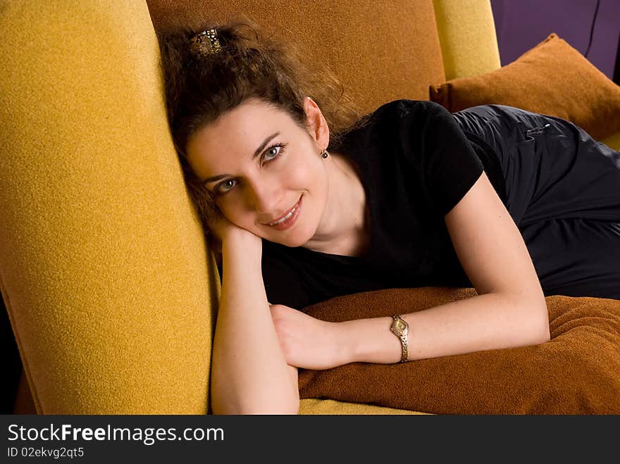 Young brunette with curly hair resting on the couch. Young brunette with curly hair resting on the couch