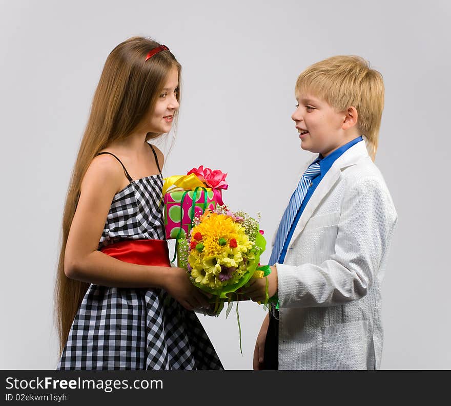 Little boy with flowers in their hands gives a gift a beautiful girl. Little boy with flowers in their hands gives a gift a beautiful girl