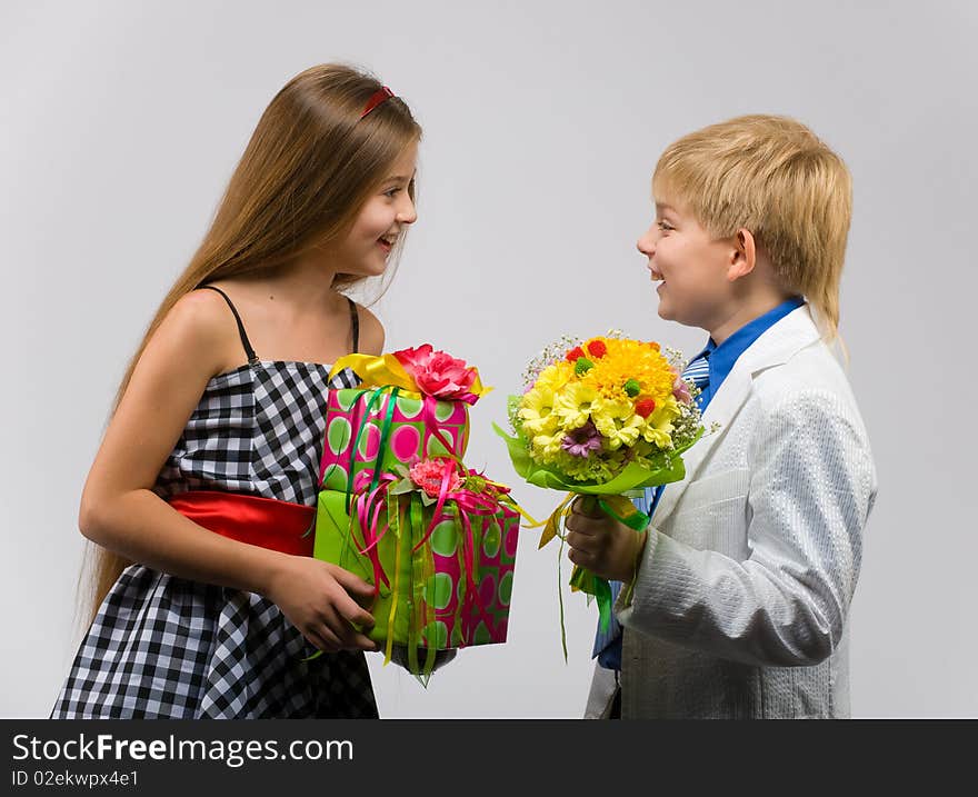 Little boy with flowers in their hands gives a gift a beautiful girl. Little boy with flowers in their hands gives a gift a beautiful girl