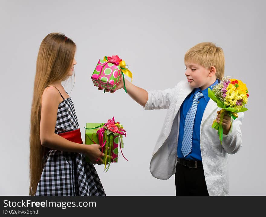 Little boy with flowers in their hands gives a gift a beautiful girl. Little boy with flowers in their hands gives a gift a beautiful girl