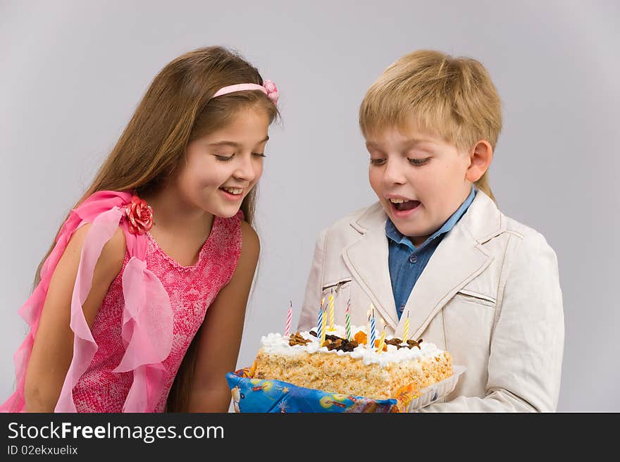 Girl in a pink dress with a cake in his hand standing next to a boy. Girl in a pink dress with a cake in his hand standing next to a boy