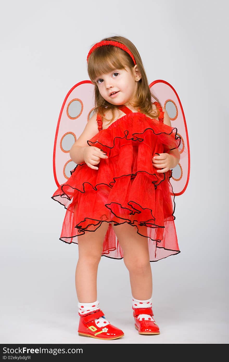 Little girl in a red dress and wings behind. Little girl in a red dress and wings behind