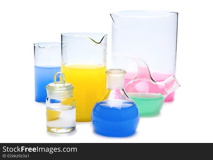 Transparent chemical glassware with red, green, yellow and blue solution isolated on white