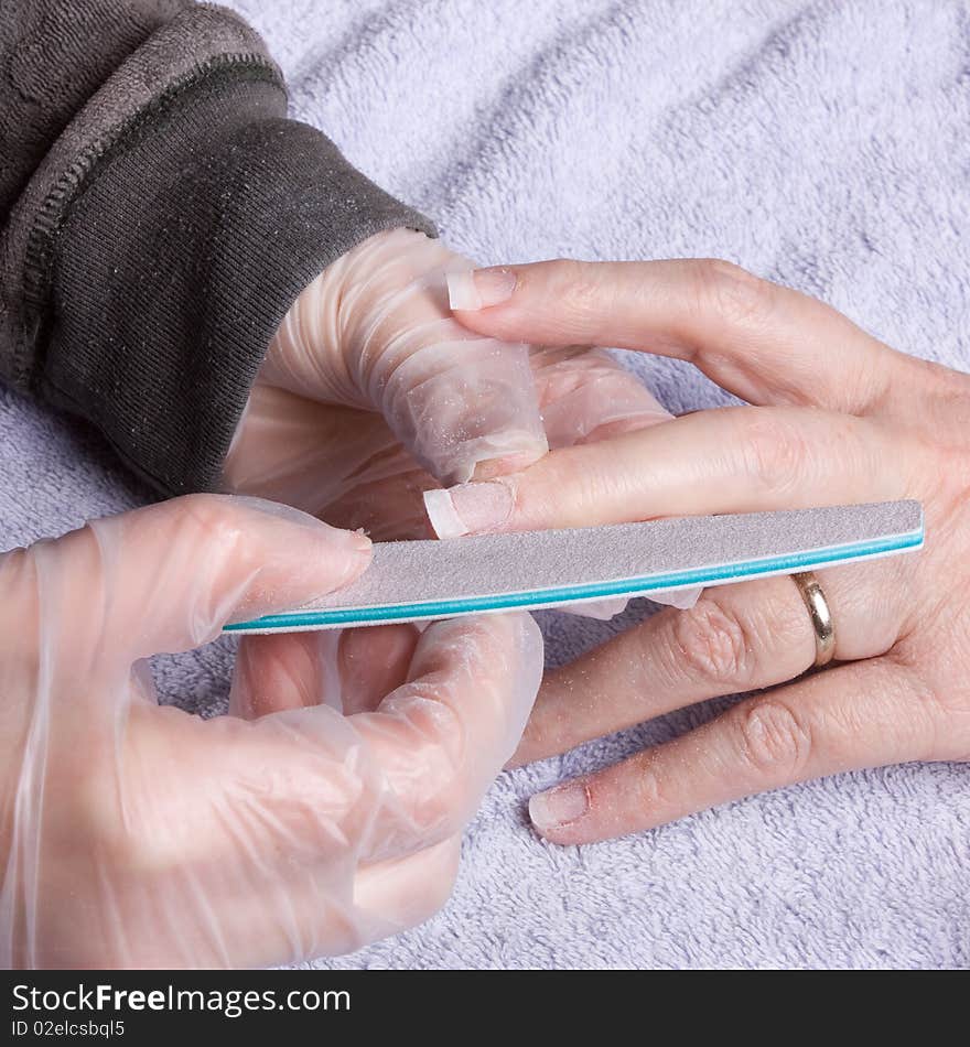 Older senior woman's hand receiving home spa/beauty treatment of nail extensions.