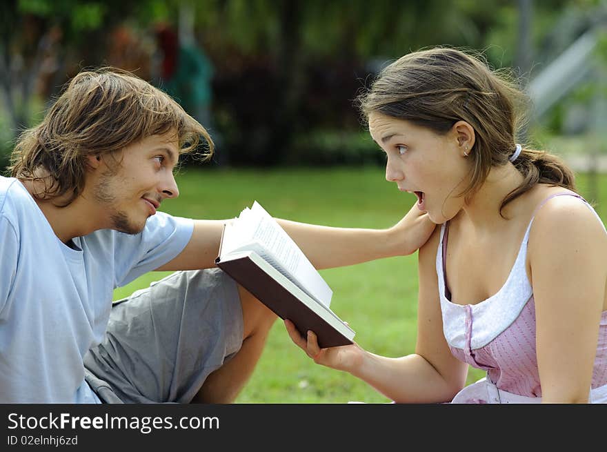 Attractive couple read together in the park. Attractive couple read together in the park