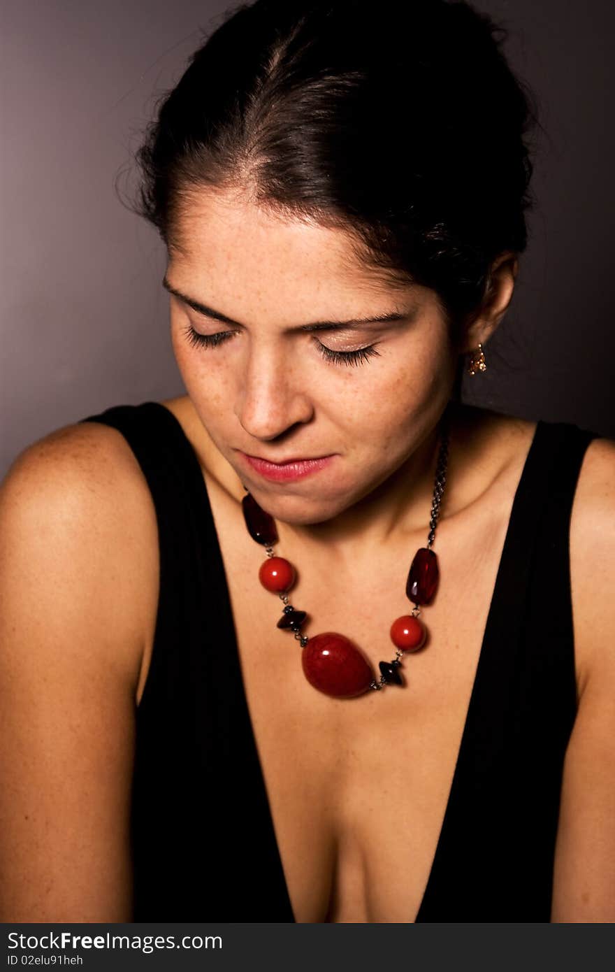 Beautiful woman with red beads looking down. Beautiful woman with red beads looking down