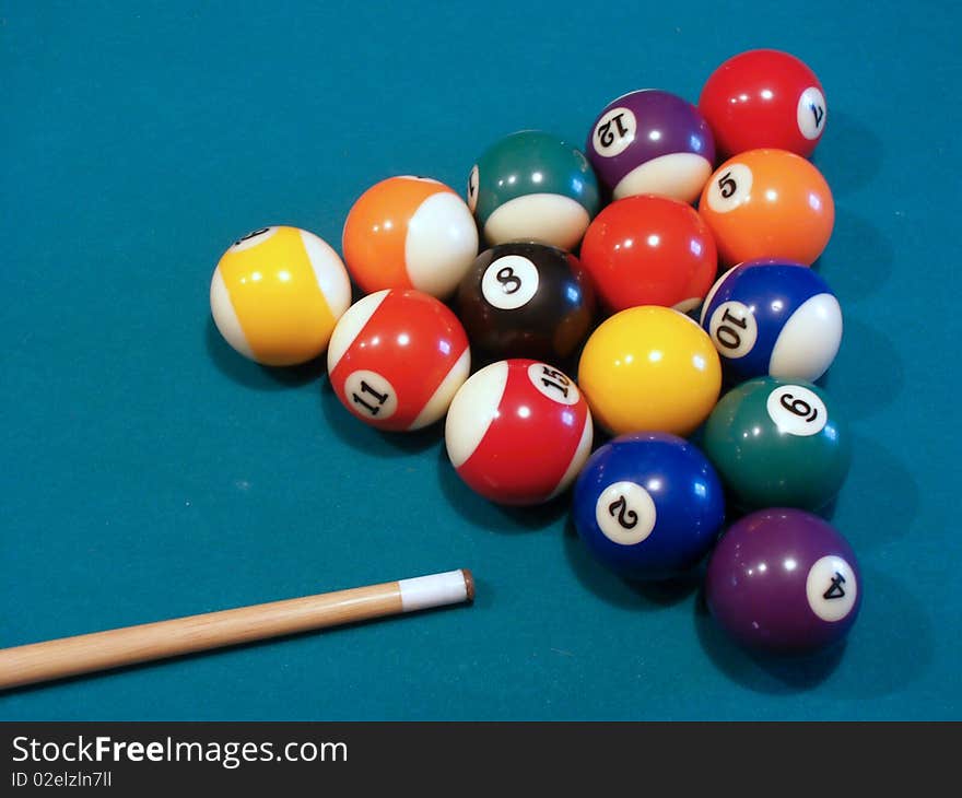 Billiard balls on green table with cue