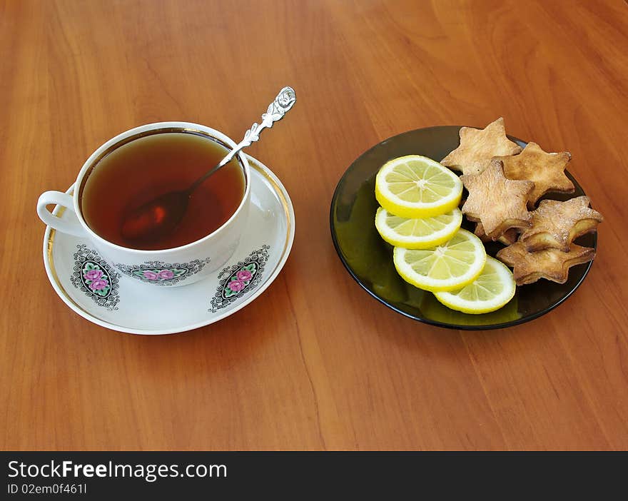 Teacup and homemade cookies with slices of lemon on plate. Teacup and homemade cookies with slices of lemon on plate