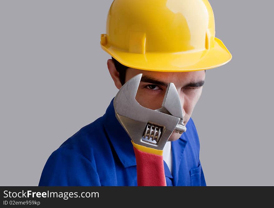 Engineer wearing blue overhauls and yellow hardhat.Looking throught a adjustable wrench. Engineer wearing blue overhauls and yellow hardhat.Looking throught a adjustable wrench.