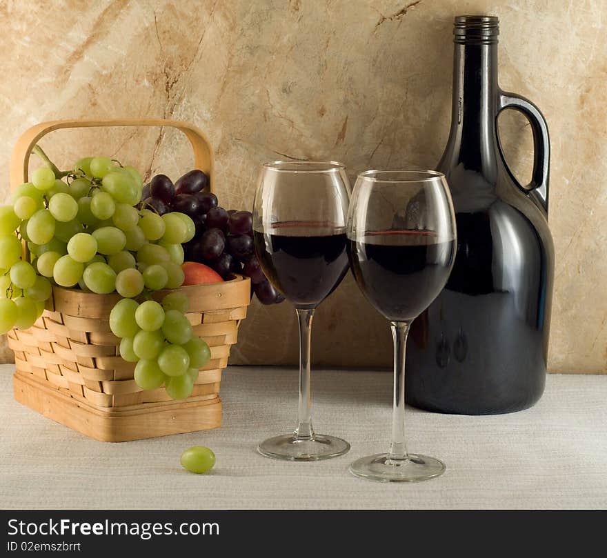 Two glasses of red wine and grapes in a basket. Two glasses of red wine and grapes in a basket