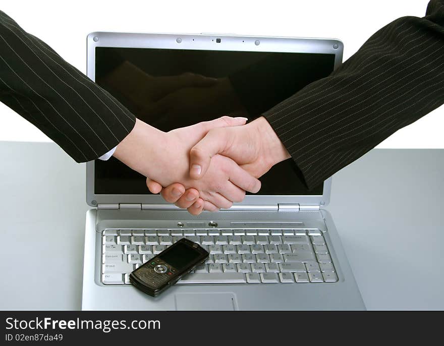 Man and woman shaking hands in front of computer and phone