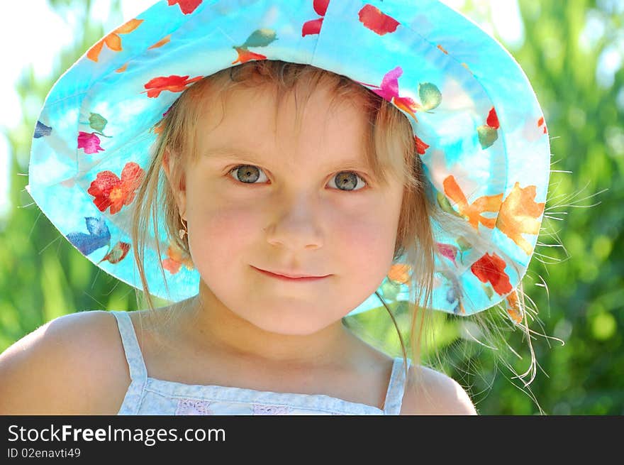 Little girl with a blue hat outdoor on a sunny summer day. Little girl with a blue hat outdoor on a sunny summer day