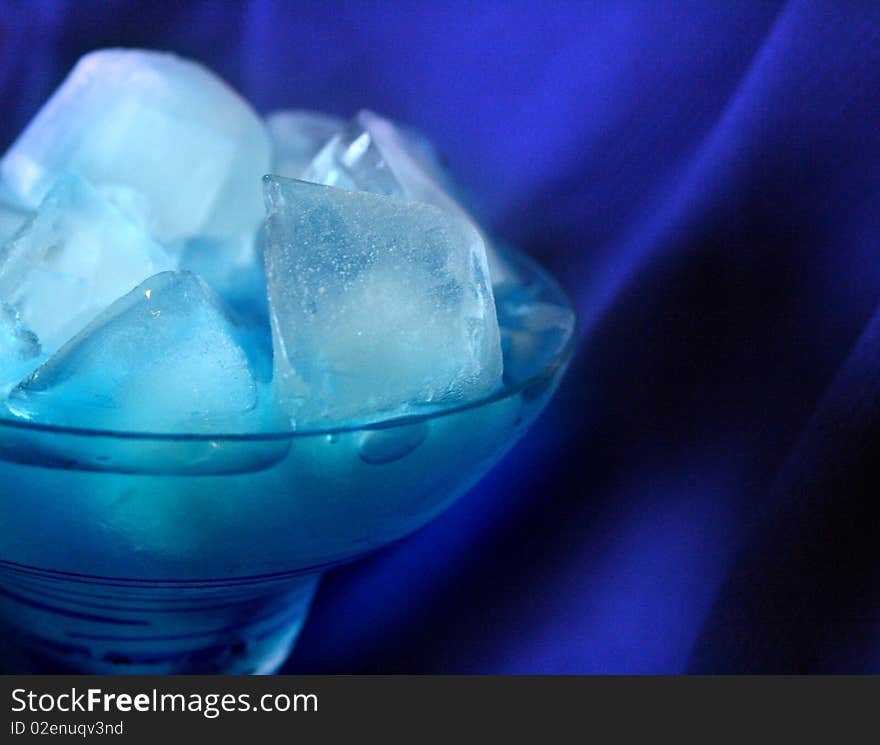 Blue drink in margarita glass full of ice cubes on blue background. Blue drink in margarita glass full of ice cubes on blue background