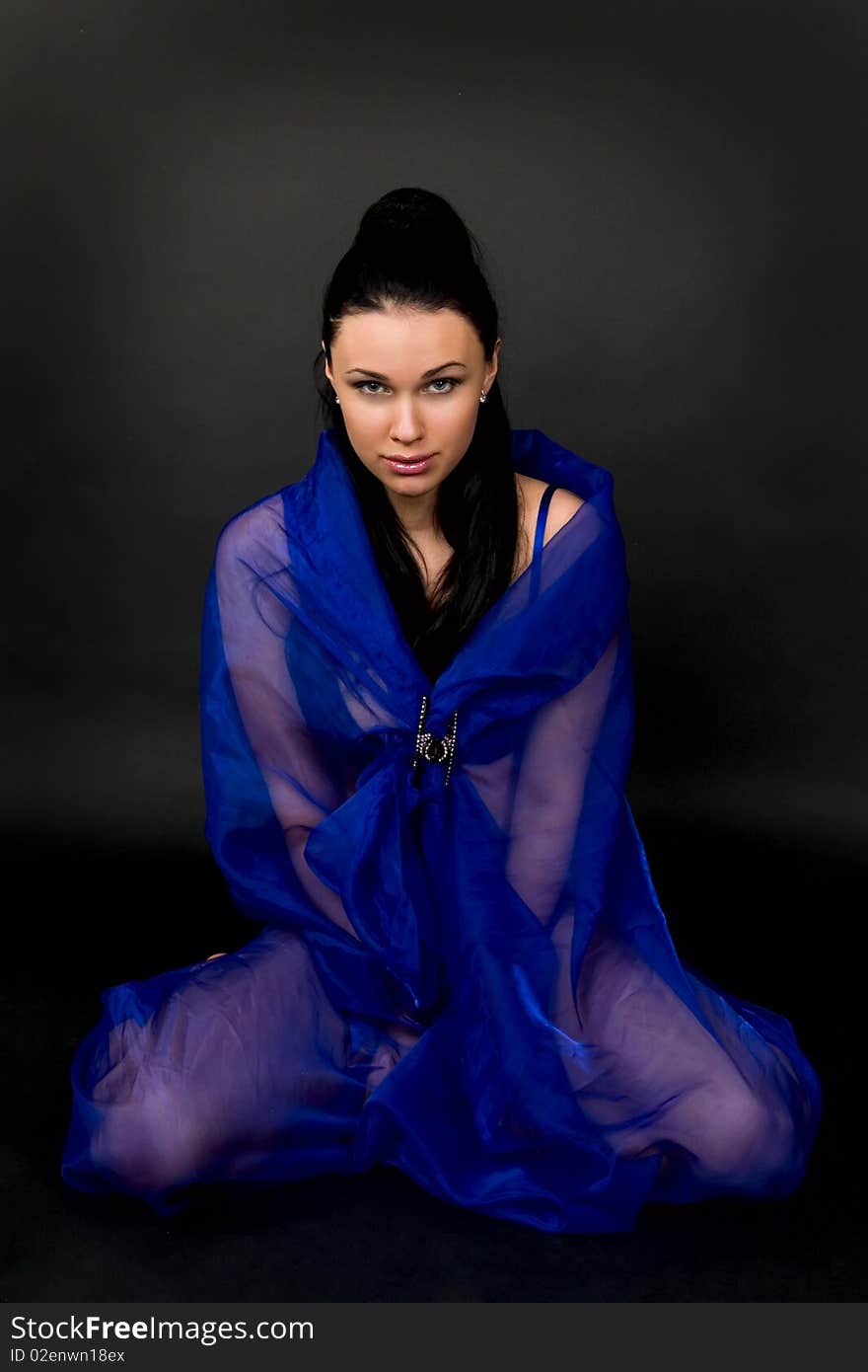 Woman in a transparent dark blue cape on a black background