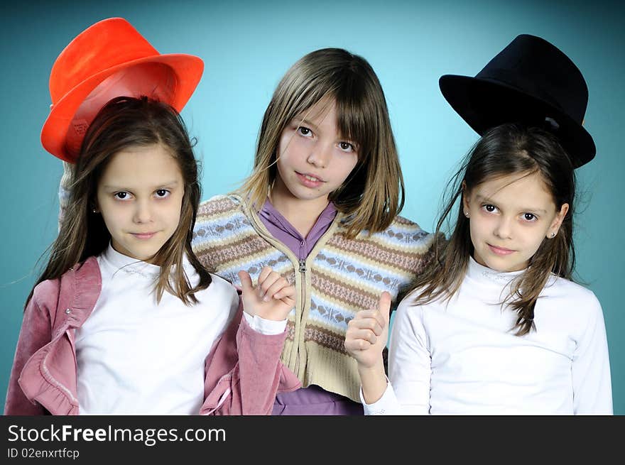 Three white children playing with black and orange hat, turquoise background. Three white children playing with black and orange hat, turquoise background