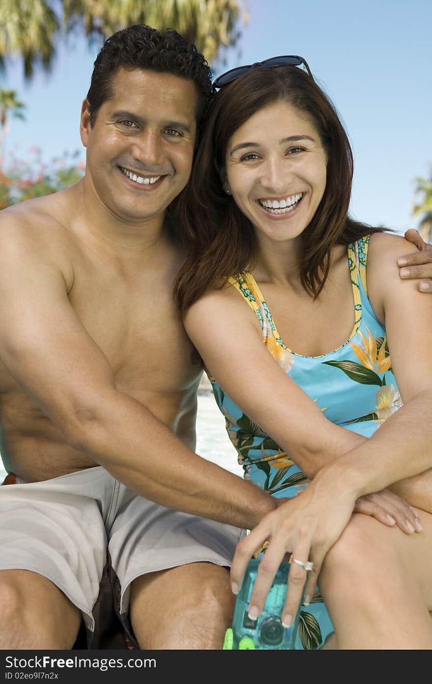 Couple sitting outdoors embracing, portrait.