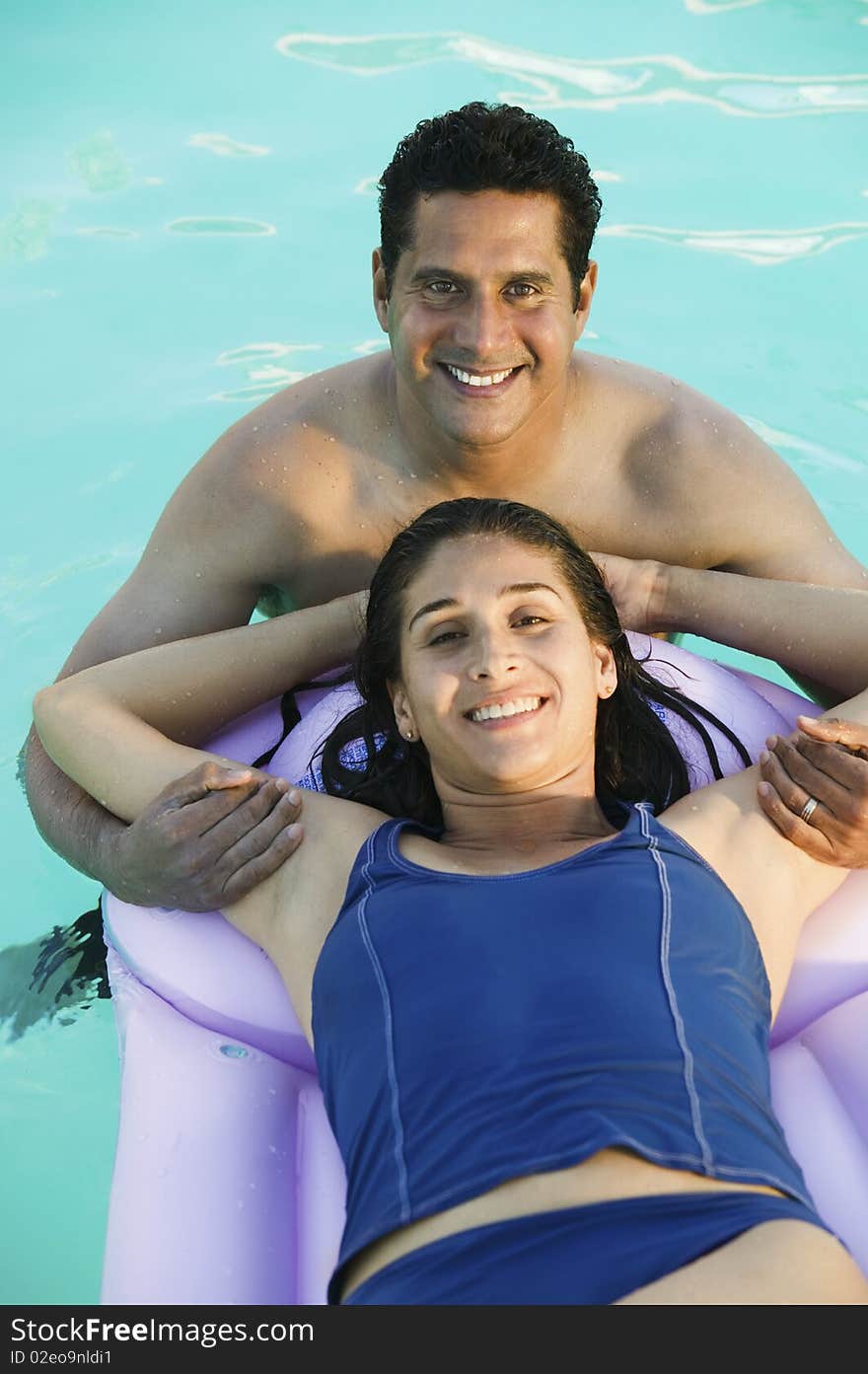 Couple in Swimming Pool, woman lying on inflatable raft, elevated view portrait.