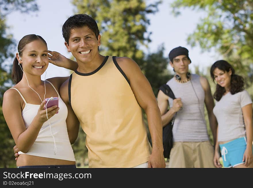 Two young couples outdoors, one woman listening to portable music player.