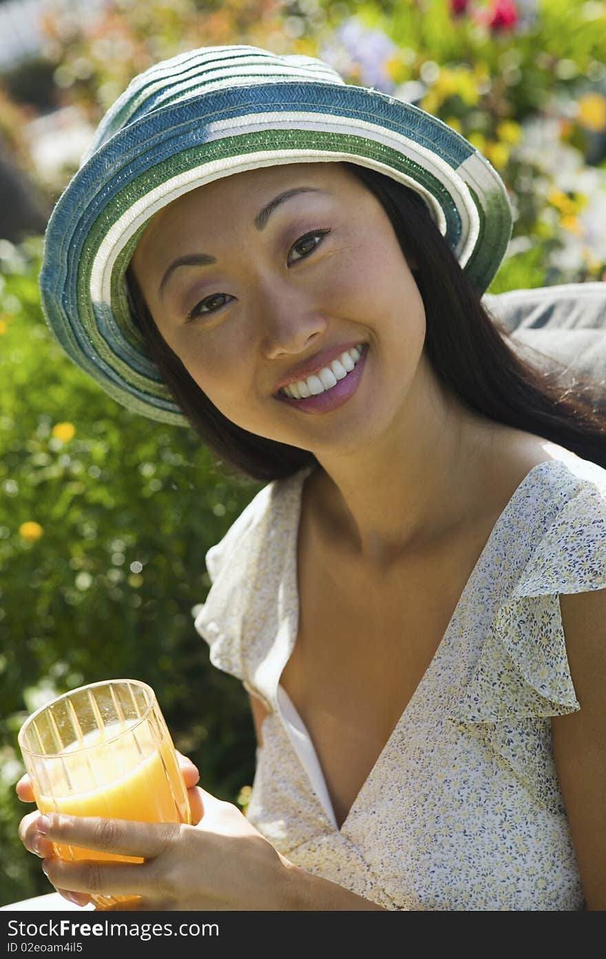 Woman drinking orange juice, outdoors, (portrait)