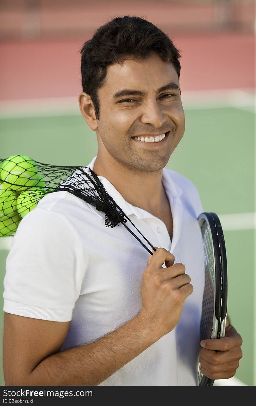 Man on tennis court with tennis balls and racket