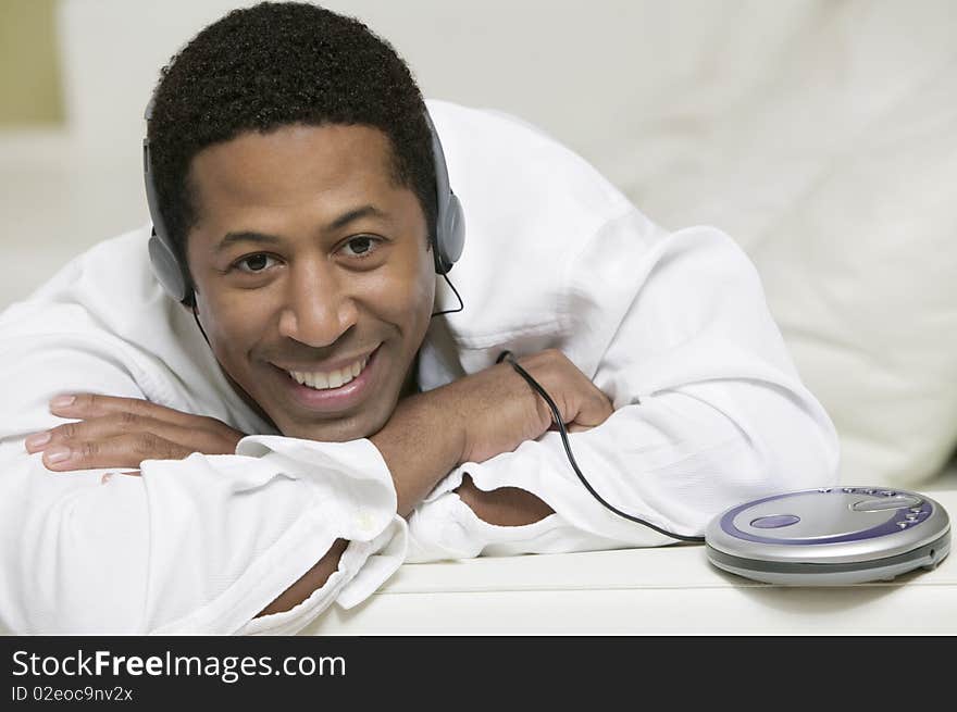 Man lying on sofa Listening to Music on portable CD player, portrait