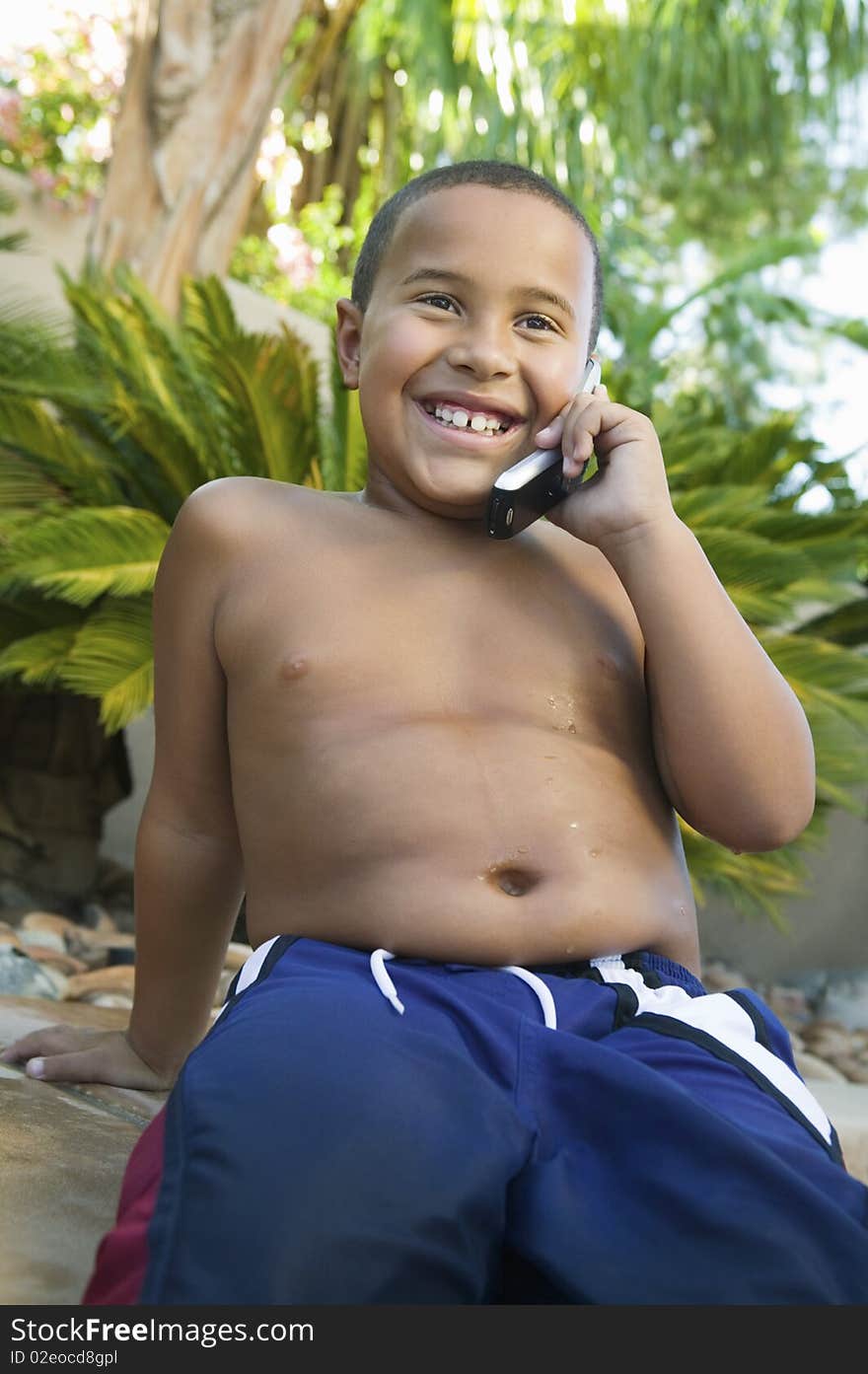 Boy sitting in back yard Using Cell Phone, front view