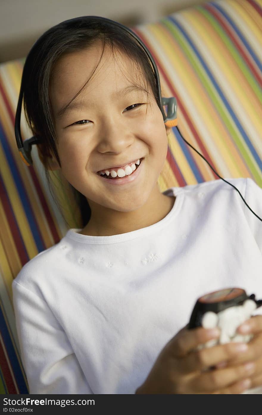 Girl sitting on sofa Listening to MP3 Player, portrait