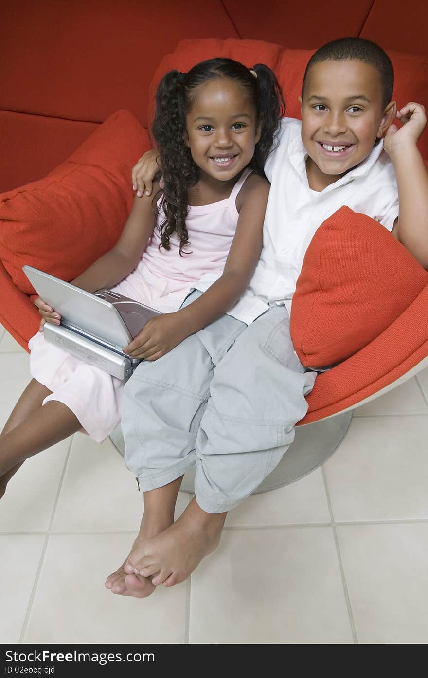 Brother and Sister in Chair with portable DVD Player, portrait. Brother and Sister in Chair with portable DVD Player, portrait