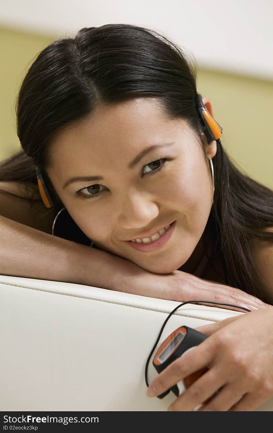 Young Woman lying on sofa Listening to MP3 Player, portrait, close up. Young Woman lying on sofa Listening to MP3 Player, portrait, close up