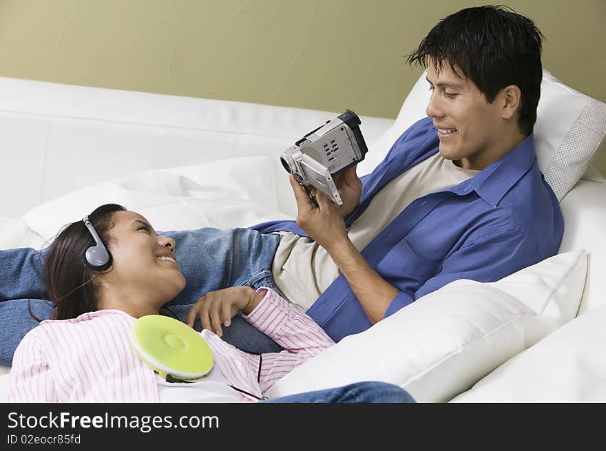 Couple on sofa, man filming partner. Couple on sofa, man filming partner